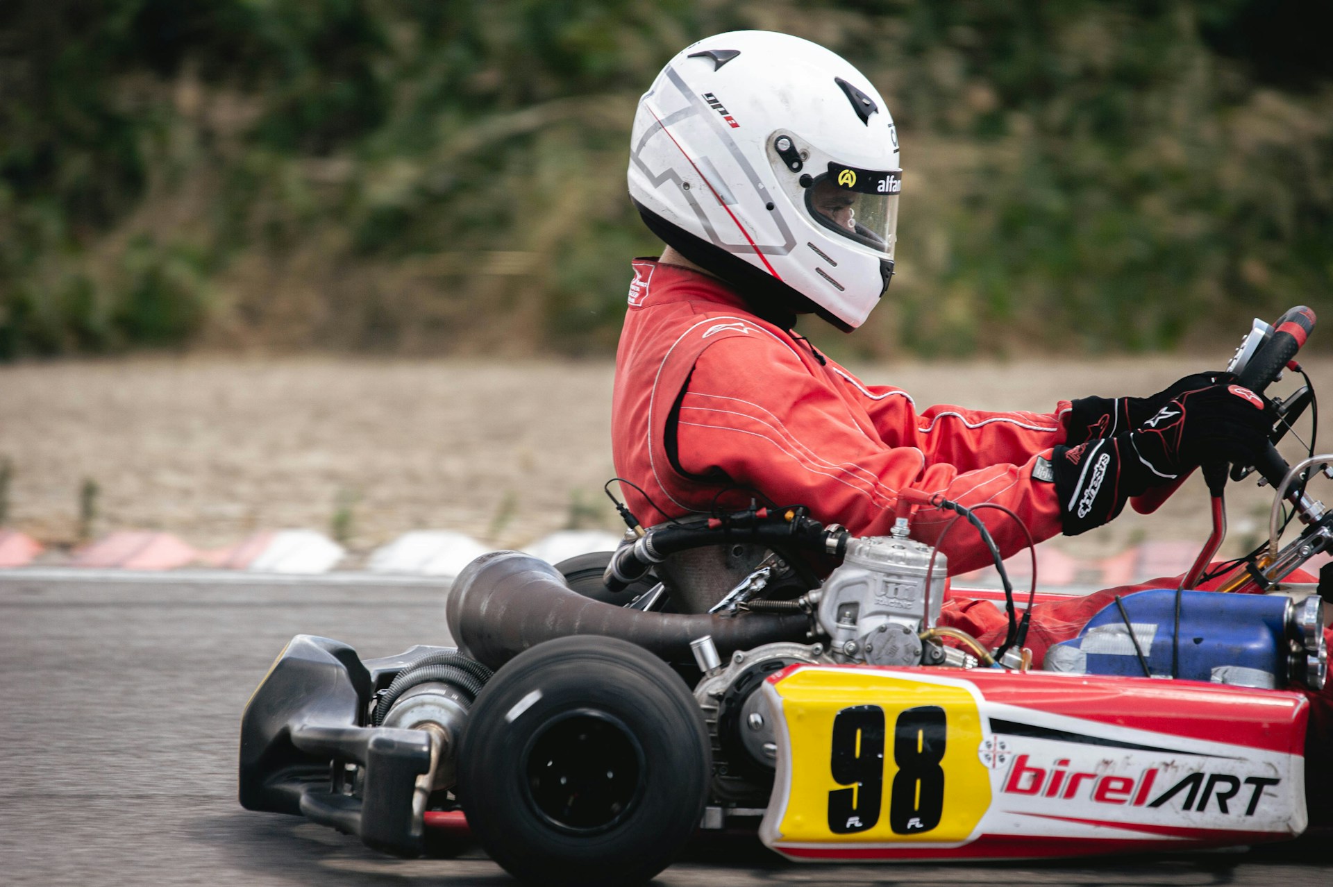 Man in white helmet, and whiteoveralls riding a go-kart